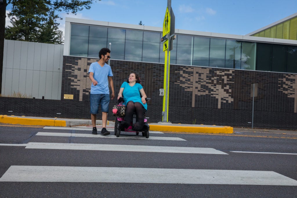 A person walking with another person using a mobility assistance device